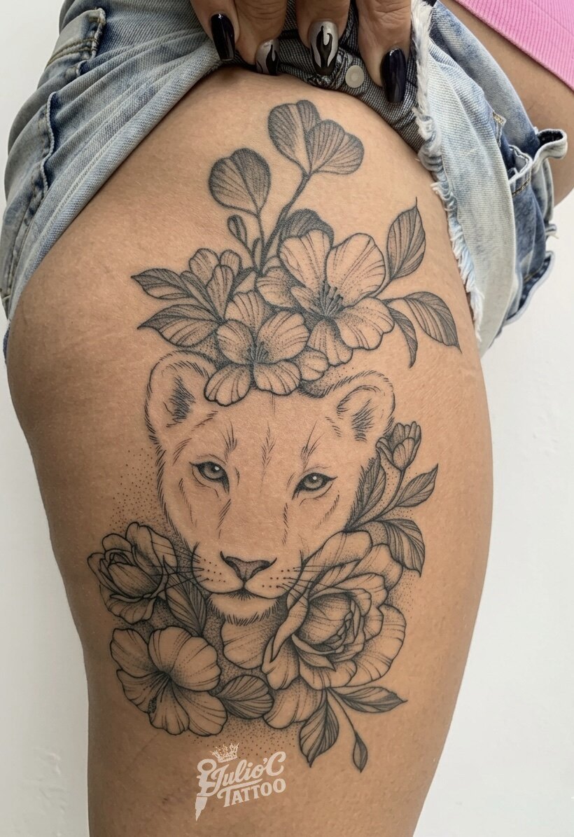 Tatuaje de leona rodeada de flores sobre la cadera