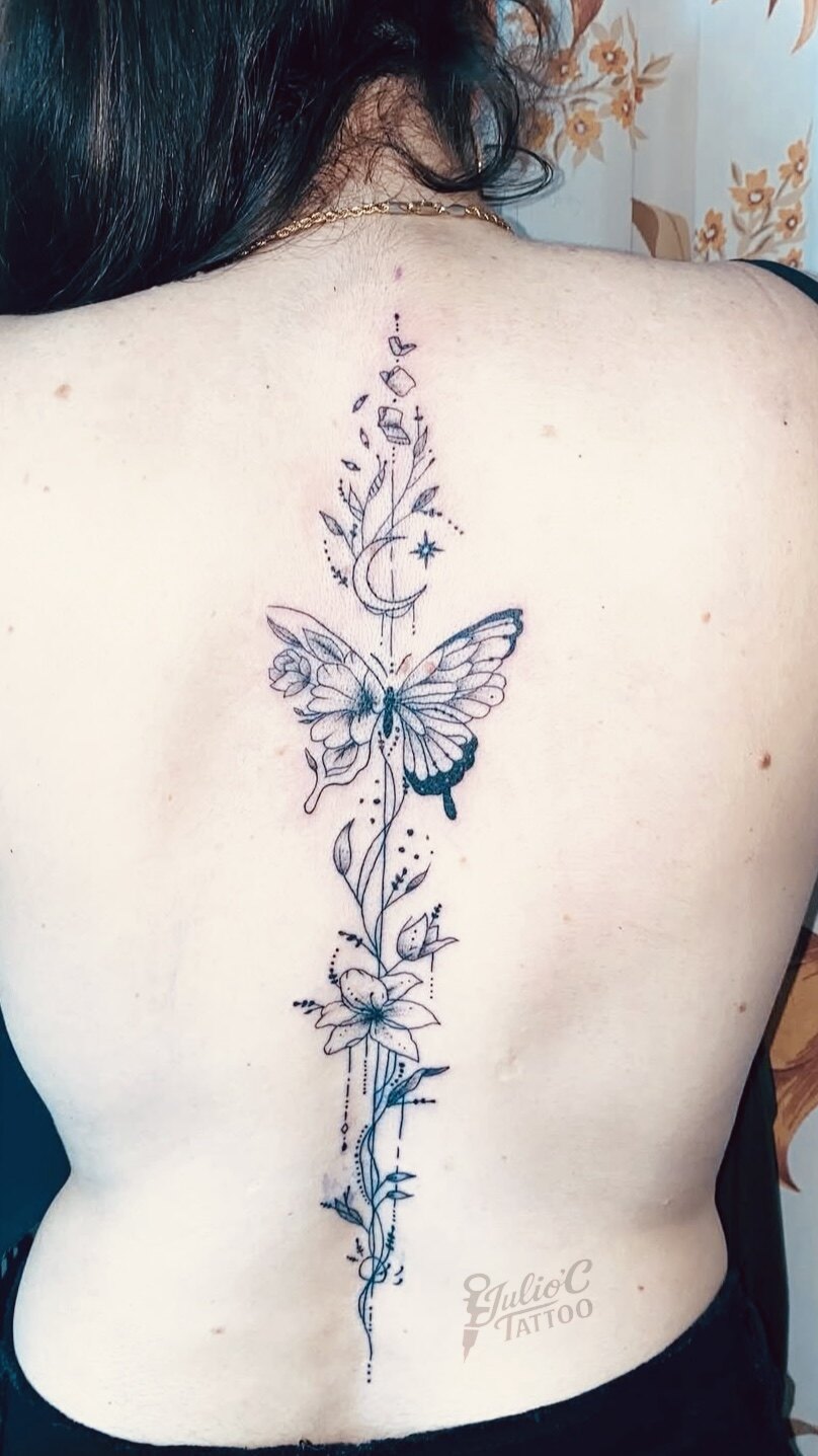 Composición vertical de mariposa, flores y luna tatuada en la espalda
