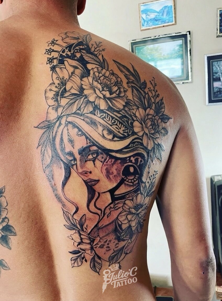 Tatuaje a color de guerrera y flores sobre la espalda y el hombro
